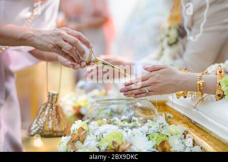 Holy water pouring ceremony over bride and groom hands, Thai traditional wedding engagement Stock Photo