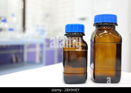 No label amber glass bottle with clear liquid chemical inside a laboratory with copy space. Stock Photo