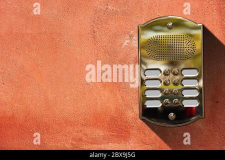 Close-up of a brass intercom with eight doorbells on a red wall  with copy space, Italy, Europe Stock Photo