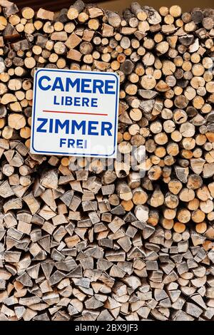 Rooms available in Italian and German language (Camere libere and Zimmer frei). Advertising sign hanging on a stack of firewood Stock Photo
