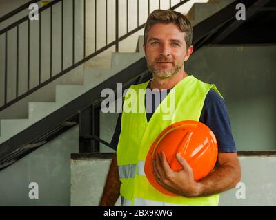 blue collar construction worker. Corporate portrait of young attractive and happy builder man or constructor posing confident smiling wearing building Stock Photo