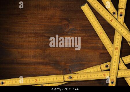 Close-up of yellow folding wooden rulers on a work table with copy space and dark shadows Stock Photo