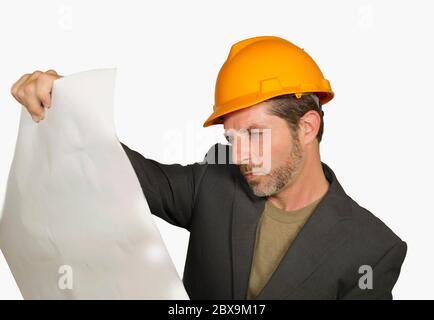 corporate portrait of young attractive and successful industrial engineer or architect in safety builder helmet checking building project blueprint ha Stock Photo
