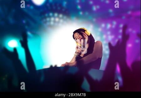 young attractive and cool Asian Japanese DJ woman with headphones at night club remixing techno music with lights background in clubbing fun and Deeja Stock Photo