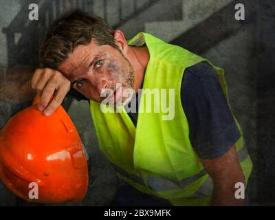 blue collar job lifestyle. Portrait of attractive and exhausted construction worker in helmet and vest at building site taking a breath during a hard Stock Photo