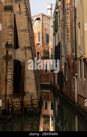 Venice, narrow canal of the lagoon and old houses. In the foreground the lower part of the bell tower of Santo Stefano church. Veneto, Italy, Europe Stock Photo