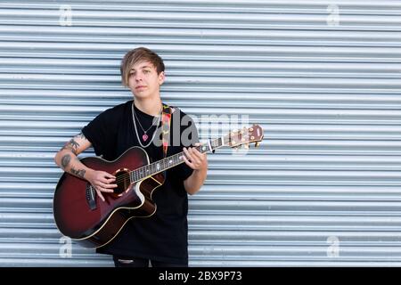 Woodbridge, Suffolk, UK September 20 2020: A 20 something female relaxing and playing an acoustic guitar outside for passers by to listen too Stock Photo