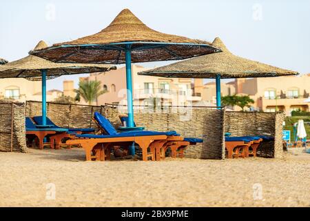 Group of straw umbrellas and deck chairs in a Red Sea sandy beach, tourist resort near Marsa Alam, Egypt, Africa Stock Photo