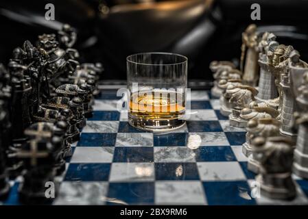 A glass of elite alcohol between black and white pieces, a Harry Potter chessboard. Stock Photo