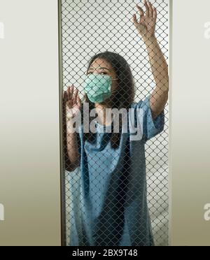 dramatic portrait of young Asian Chinese woman infected with virus victim of contagious disease or psychotic and mental insane patient locked in secur Stock Photo