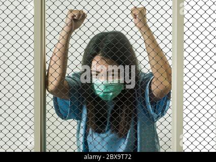 dramatic portrait of young Asian Chinese woman infected with virus victim of contagious disease or psychotic and mental insane patient locked in secur Stock Photo