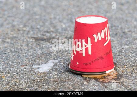 Saint John, New Brunswick, Canada - January 16, 2018: A discarded Tim Hortons coffee cup rests upside down in a parking lot. Stock Photo