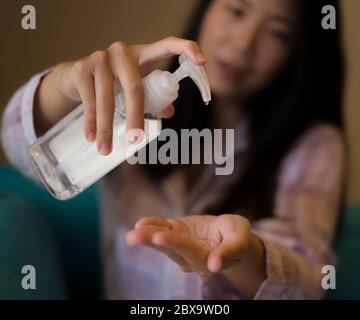 lifestyle portrait of young beautiful and responsible Asian Chinese woman at home washing her hands with alcohol sanitizer gel in prevention to covid-