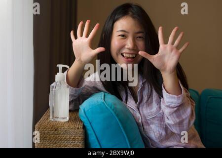lifestyle portrait of young beautiful and responsible Asian Chinese woman at home washing her hands with alcohol sanitizer gel in prevention to covid-