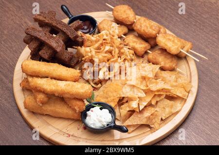 Potato chips, tortilla chips with crispy bread. Sauces on wooden board Stock Photo
