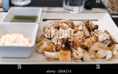 Grilled squid, grilled cuttlefish served as a Spanish sepia tapa with garlic oil and a chopped garlic and parsley Stock Photo