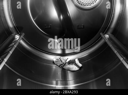 One Sock in an Empty Stainless Steel Dryer for Lost Sock Day on May 9 in Black and White Stock Photo