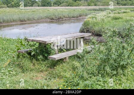 Empty public picnic table in sunshine beside the waters of the River Fowey at Lostwithiel, Metaphor empty public spaces during Covid-10 lockdown. Stock Photo