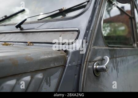 Oblique front view with front door and air inlet valve of an old run-down car (Citroen 2CV) in the Netherlands. Focus on the door handle Stock Photo