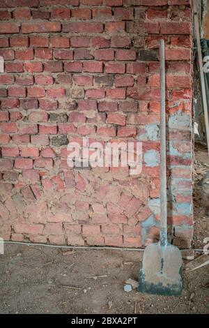 on a building site there is a shovel on a brick wall Stock Photo
