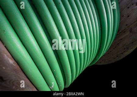 Wooden coil of green Electric Cable outdoor. Isolated on black Stock Photo