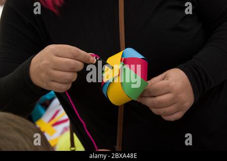 hands holding a homemade mult-colored pinwheel against a black shirt Stock Photo
