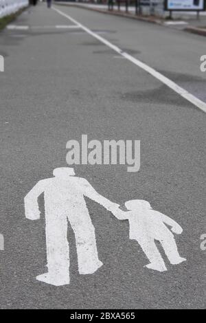 Walking man and child pavement sign painted white on a concrete way Stock Photo