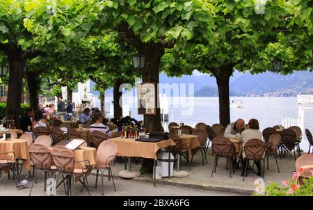 BELLAGIO, ITALY - May 23, 2013: Illustrative editorial - People eating on restaurant terrace on the side of the lake, in Bellagio port, Lake Como, Lom Stock Photo