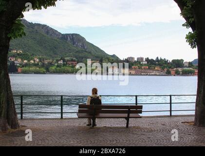 LECCO, ITALY - May 24, 2013: Tourist resting on bench looking at the lake Stock Photo