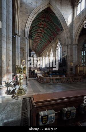 St. Botolph's Church interior in Boston with sun shining through windows highlighting gold coloured lectern and casting eagle shaped shadow on wall. Stock Photo