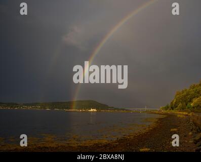 Triple rainbows display against a dark sky above North Kessock and the Beauly firth near Inverness, Scotland Stock Photo