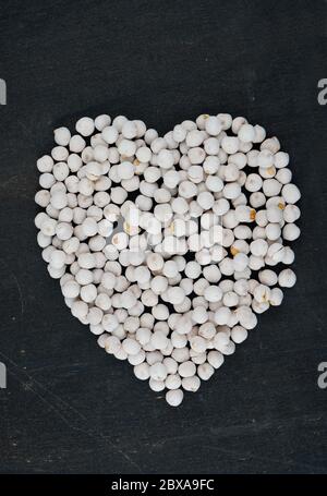 Heart shaped white roasted chickpeas on black background Stock Photo