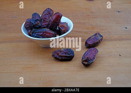 Plateful of Organic pitted dates and Spilled pitted dates on Wooden Background Stock Photo