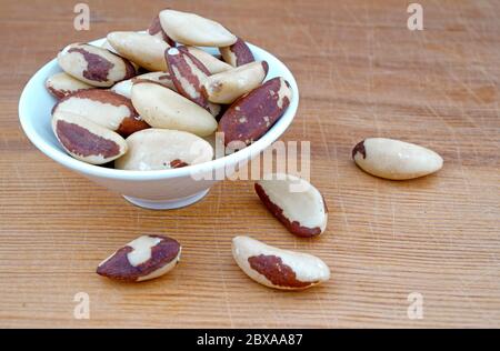 Plateful of Organic Brazil nuts and Spilled Brazil nuts on Wooden Background Stock Photo