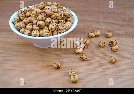 Plateful of Organic Roasted spicy chickpeas and Spilled chickpeas on Wooden Background Stock Photo