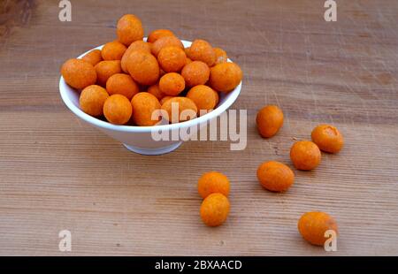 Plateful of Organic coated peanuts and Spilled coated peanuts on Wooden Background Stock Photo