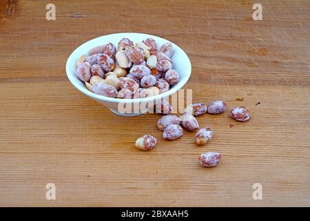 Plateful of Organic salted peanuts and Spilled salted peanuts on Wooden Background Stock Photo