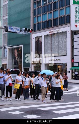 Pedestrians waiting in front of a traffic light at a zebra crossing in Ginza. Ginza is a popular shopping district famous for its luxury stores.