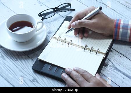 person hand writing on notepad at office desk  Stock Photo