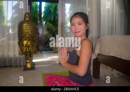 yoga against lockdown quarantine stress - young beautiful and happy Asian Korean woman doing yoga workout at home bedroom practicing relaxation and me Stock Photo