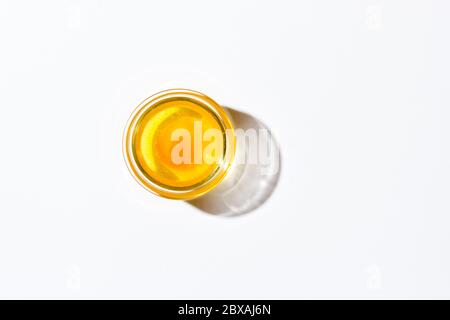 Honey in a small glass plate on a white background. Nearby lies a wooden spoon Stock Photo