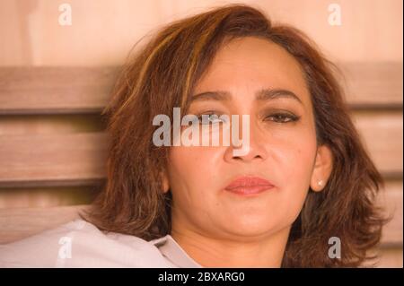 portrait of attractive happy and beautiful mature woman aged 50s to 60s smiling cheerful and charming at home bedroom sitting on bed in the morning in Stock Photo