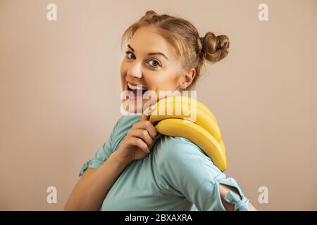Portrait of cute happy woman holding bananas. Stock Photo