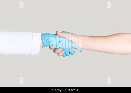 Closeup of man shaking hands with doctor in rubber glove on white background Stock Photo