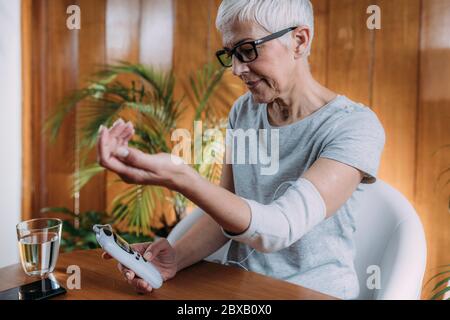 Senior woman doing elbow physical therapy with TENS Stock Photo