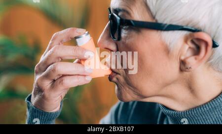 Senior woman using asthma inhaler with extension tube Stock Photo