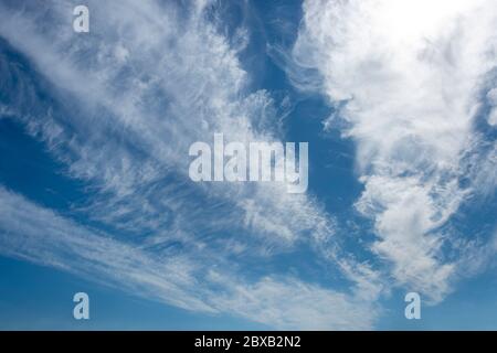A bright blue sky with white whispy clouds Stock Photo
