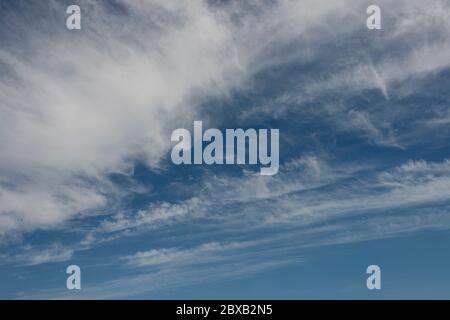 A bright blue sky with white whispy clouds Stock Photo