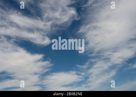 A bright blue sky with white whispy clouds Stock Photo