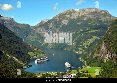 View of Geiranger and Geirangerfjord from the Flydalsjuvet viewpoint, with two cruise ships anchored in the fjord. Stock Photo